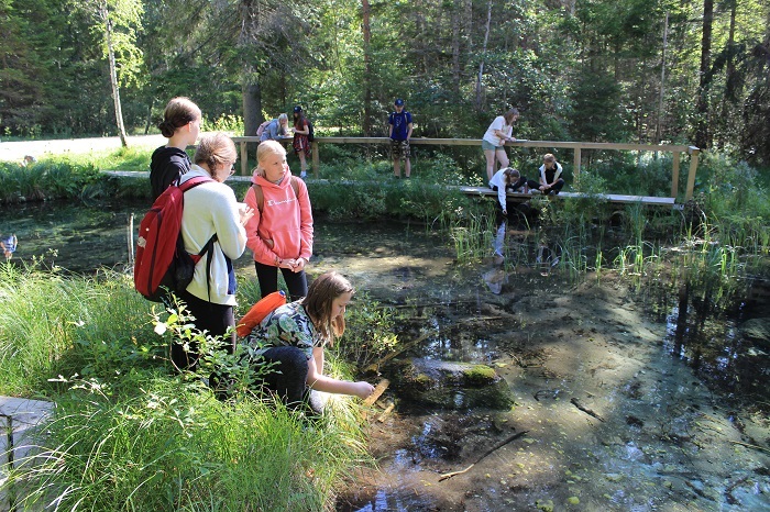 noored looduskaitsjad seisavad suvisel päeval Oostriku tõusuallika juures