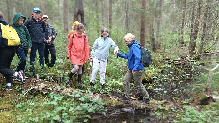 matkajad aitavad juhendajal üle oja ulatades käe