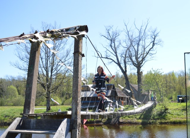 A woman walks on a suspension bridge.