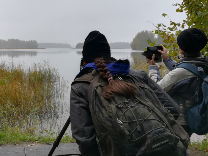 Kaks naist seisavad seljaga ja püüavad nende ees laiuvat udust järvevaadet pildile saada.