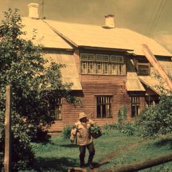 Kollakaspruunide värvidega vanal fotol vana mees korviga maja ees õunapuude vahel 1970ndatel
