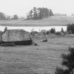 Mustvalgel fotol vana laastukatusega palkhoone järve kaldal